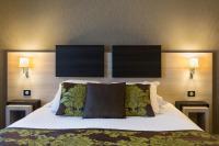 a bedroom with a large bed with two lamps on the wall at Best Western Plus Richelieu in Limoges