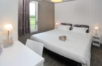 a white bedroom with two beds and a window at Domaine De Barres in Langogne