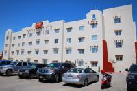 Un gran edificio blanco con coches aparcados en un estacionamiento. en Hotel Zar La Paz, en La Paz
