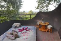 a bed in a tent with a table and flowers at Sphair perchée in Fisenne