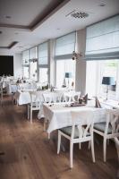 a restaurant with white tables and chairs and windows at Hotel Waastwinj in Utersum