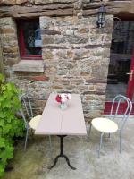 a table with two chairs and a vase of flowers on it at Le Logis De Judicael in Paimpont