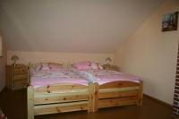 a bedroom with a wooden bed with pink sheets at Gasthof Zum Stausee in Engelskirchen
