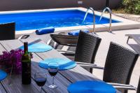 a table with wine glasses and a bottle of wine by a pool at Villa Periska Komiža in Komiža