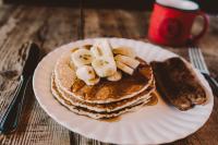 a stack of pancakes with bananas and syrup on a plate at Oceanpoint Ranch in Cambria