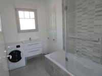 a white bathroom with a washing machine and a bath tub at Villa du Cabestan in Andernos-les-Bains