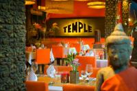 a restaurant with tables with orange chairs and a statue at Golden Temple Hotel in Siem Reap