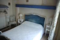 a bedroom with a large bed with a blue headboard at Les Fleurs in Monpazier