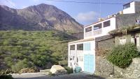 a house with a blue door in front of a mountain at ponta gato residence in Tarrafal