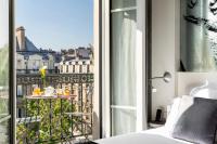 a room with a bed and a balcony with a table at Hotel Marais Grands Boulevards in Paris