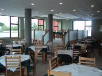 una sala da pranzo con tavoli, sedie e finestre di O Vendaval Hostal Restaurante a Barreiros
