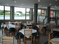 una sala da pranzo con tavoli, sedie e finestre di O Vendaval Hostal Restaurante a Barreiros