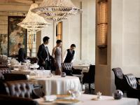 a group of men standing in a restaurant with tables at Four Seasons Hotel Hong Kong in Hong Kong