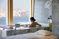 a woman sitting in a bath tub in a window at Four Seasons Hotel Hong Kong in Hong Kong