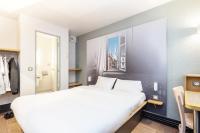 Un dormitorio con una gran cama blanca y un escritorio. en B&amp;B HOTEL Bayonne, en Bayona