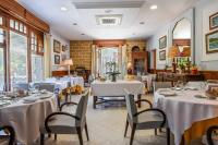 Un comedor con mesas y sillas blancas. en Logis Hotel & Restaurant Bergeret Sport, en Hendaya