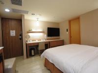 a hotel room with a bed and a desk and a television at Kindness Hotel - Tainan Chihkan Tower in Tainan