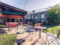 Un patio con mesas y sillas frente a un edificio. en Mercure Bourg En Bresse, en Bourg-en-Bresse