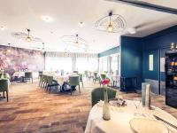 Un restaurante con mesas y sillas blancas y paredes azules. en Mercure Bourg En Bresse, en Bourg-en-Bresse
