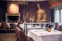 a restaurant with white tables and chairs and a statue at Van der Valk Hotel Groningen-Westerbroek in Westerbroek