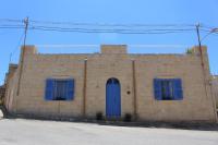 a brick building with blue shutters and a blue door at Simar in Qala