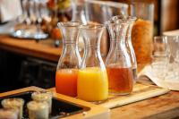 three glass vases filled with orange juice on a table at Hotel Lehenerhof in Salzburg