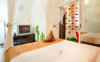 a bedroom with a bed with a tv and a cactus wall at sweet home B&amp;B in Hualien City