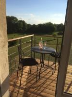 a table and chairs on a balcony with a view of a field at Les petits chenes in La Pellerine