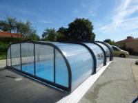 a glass house with a swimming pool in a parking lot at Le Chêne Liège in Maché