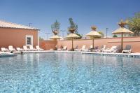 a swimming pool at a hotel with chairs and umbrellas at Résidence Odalys Fleur de Sel in Aigues-Mortes