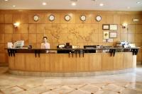 a woman standing at a counter in a lobby with clocks at Oriental Hotel in Tainan