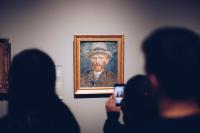 a person taking a picture of a painting of a man at Hotel Espresso in Amsterdam