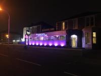 un edificio con luces púrpuras en una calle por la noche en The Windsor Hotel and Bar, en Kirkcaldy