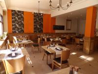 un restaurante con mesas y sillas de madera y paredes de color naranja en Come Inn, en Neufchâtel-en-Bray