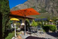 una mesa con una sombrilla naranja frente a una casa en Relais de la Sarvaz, en Saillon