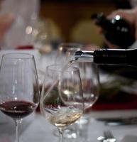 una persona que vierte vino en copas de vino sobre una mesa en Hotel Gasthof Mitteregger - BEST PLACE in town with summercard included, en Kaprun