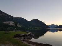 a lake with a bench and mountains in the background at Nina´s Appartement Bad Mitterndorf in Bad Mitterndorf