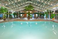 una gran piscina en un edificio con mesas y sillas en Best Western Okemos&#47;East Lansing Hotel &amp; Suites, en Okemos