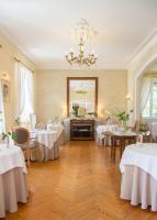 un comedor con mesas blancas y una lámpara de araña en Logis Hôtel Restaurant Château Bellevue, en Cazaubon