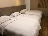three beds in a room with white sheets and pillows at The Riverside Hotel Hengchun in Hengchun South Gate