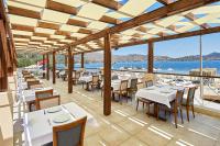 ein Restaurant mit Tischen und Stühlen und Blick auf das Meer in der Unterkunft Fİ Light Solto Boutique Beach Hotel in Selimiye