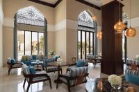 a lobby with chairs and tables and windows at Al Najada Doha Hotel by Tivoli in Doha