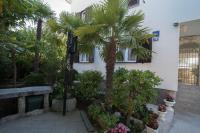 a courtyard with palm trees and plants in front of a building at Apartments Palme in Malinska