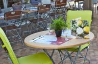 a wooden table with green chairs and a table with glasses at Campanile Lyon Sud Feyzin in Feyzin