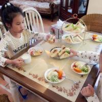 a little girl sitting at a table eating food at Hasayaki Homestay in Dayi