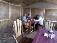 a group of people sitting around a table in a room at Mbunga Community Tourism Campsite in Kasese