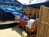 a group of men sitting at a table under a tent at Mbunga Community Tourism Campsite in Kasese
