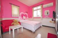 a pink bedroom with a teddy bear and a red chair at Happy Orange Homestay in Dongshan