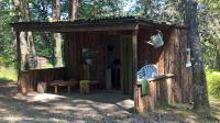 a wooden cabin with a table and chairs in the woods at La Ptite Ferme de Caro in Meyrignac-lʼÉglise