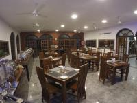 Un restaurante con mesas y sillas de madera en una sala. en Hotel Sunray, en Kandy